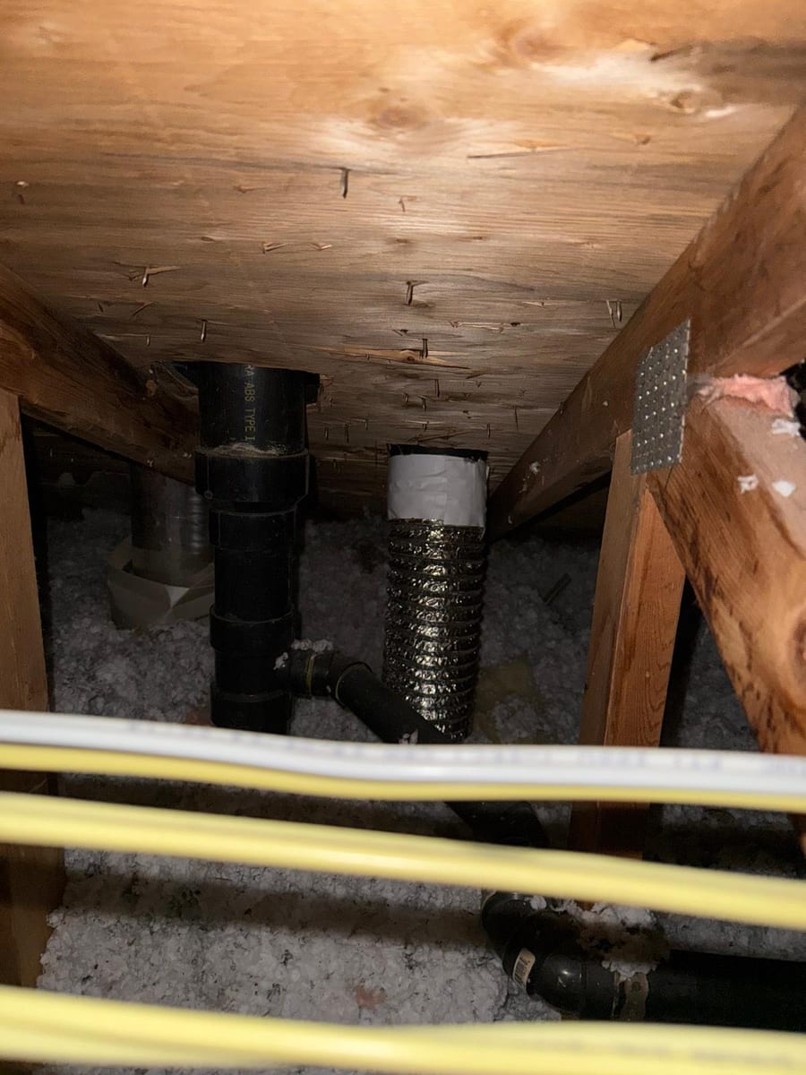 Exhaust duct discharging inside an attic above blown-in insulation