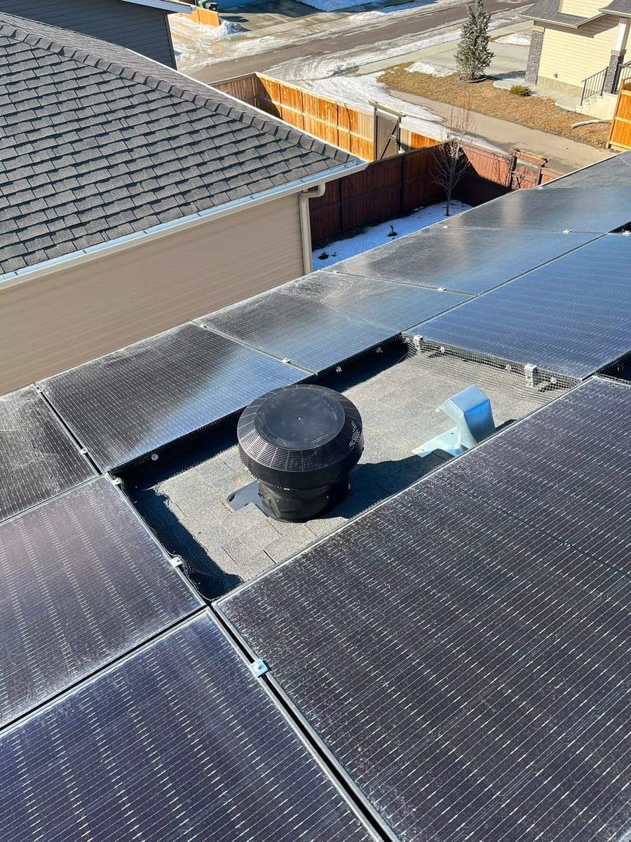 Turbine vent on a shingle roof between solar panels
