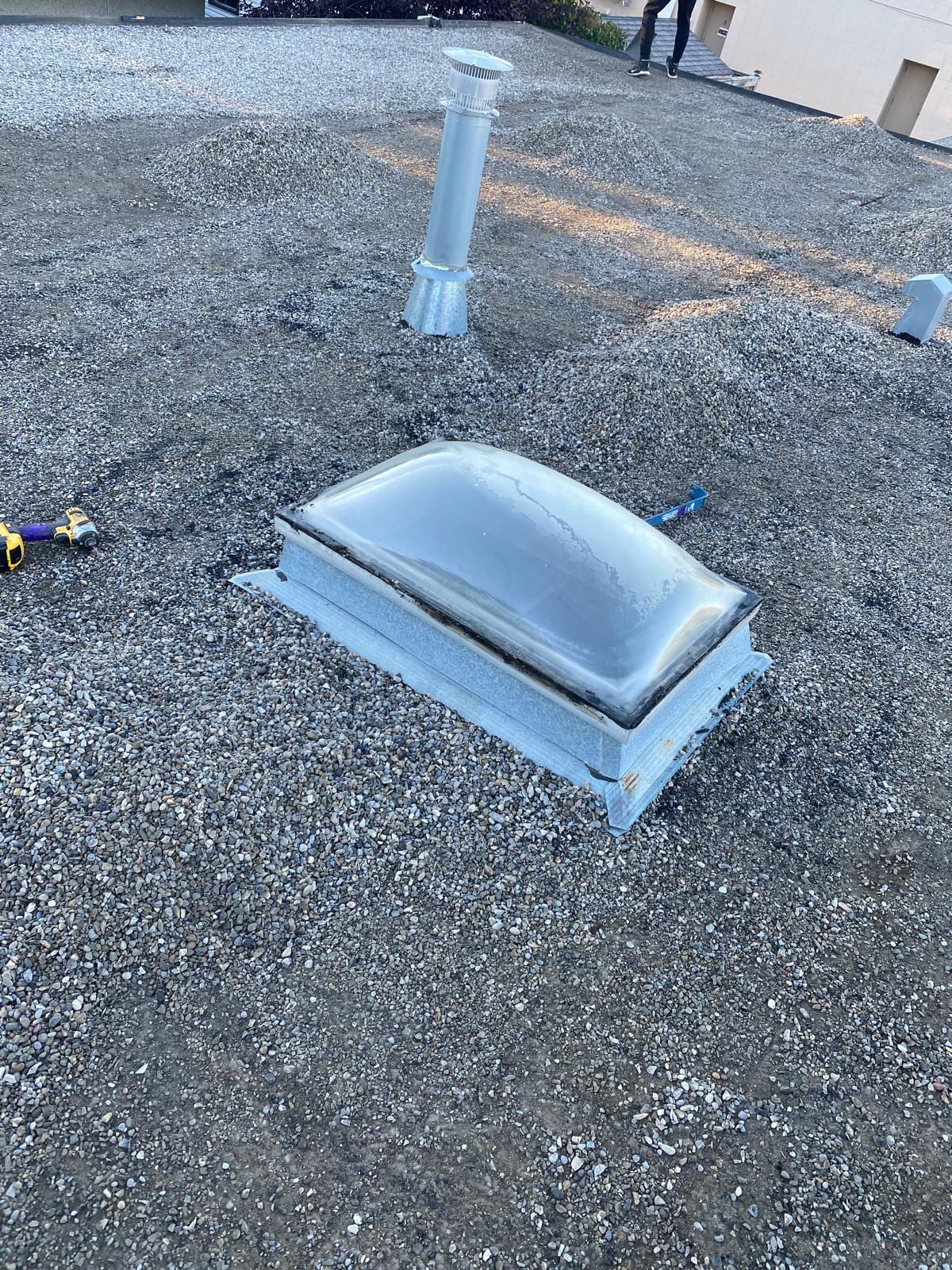 An aged dome skylight on a gravel flat roof in Calgary, the kind of unit hail takes out first