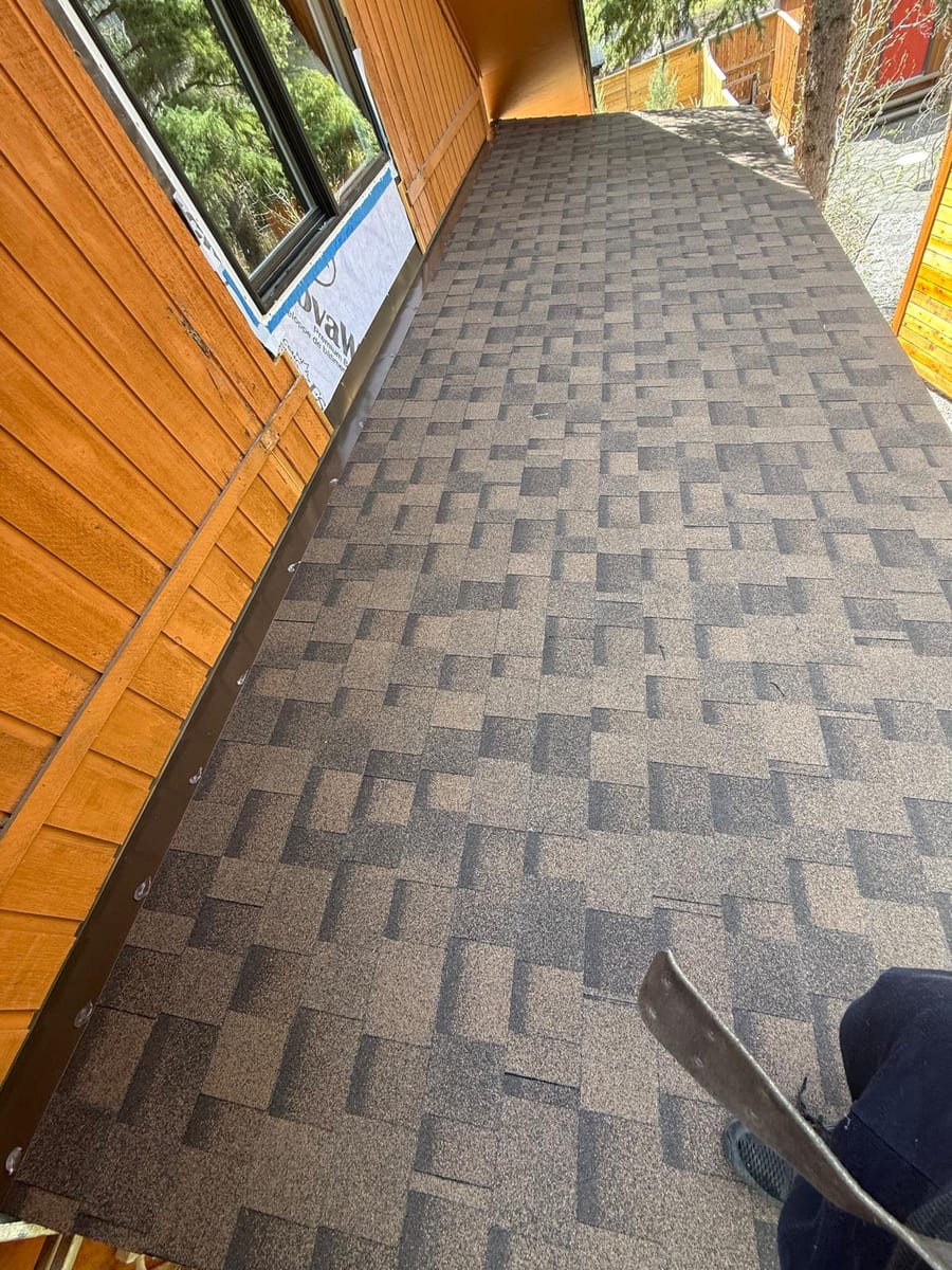 Finished low-slope shingle roof beside cedar siding, site left clean