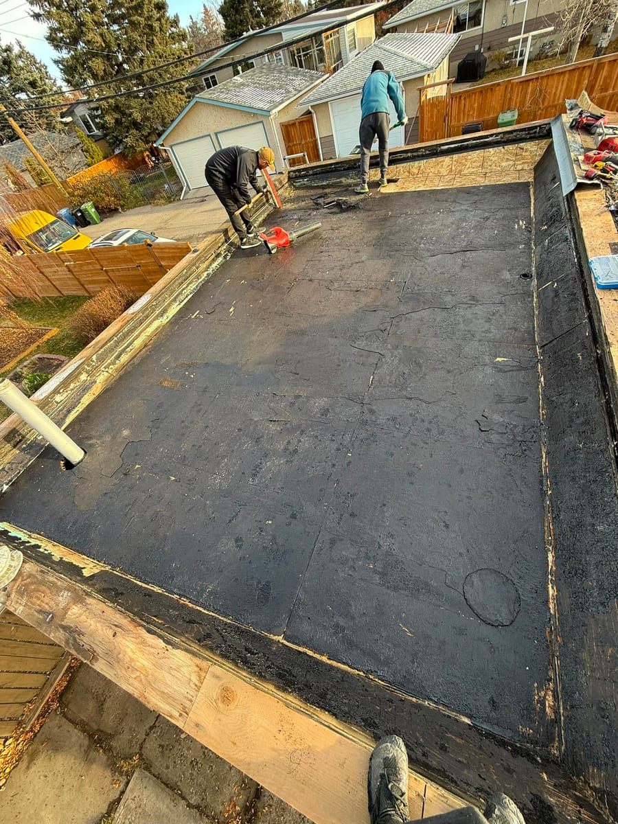Crew removing the old membrane during a flat roof tear-off in Calgary