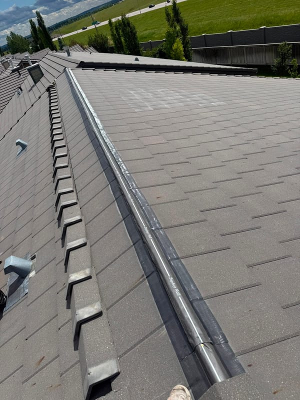 Metal valley flashing tying a tile roof into a shingle roof