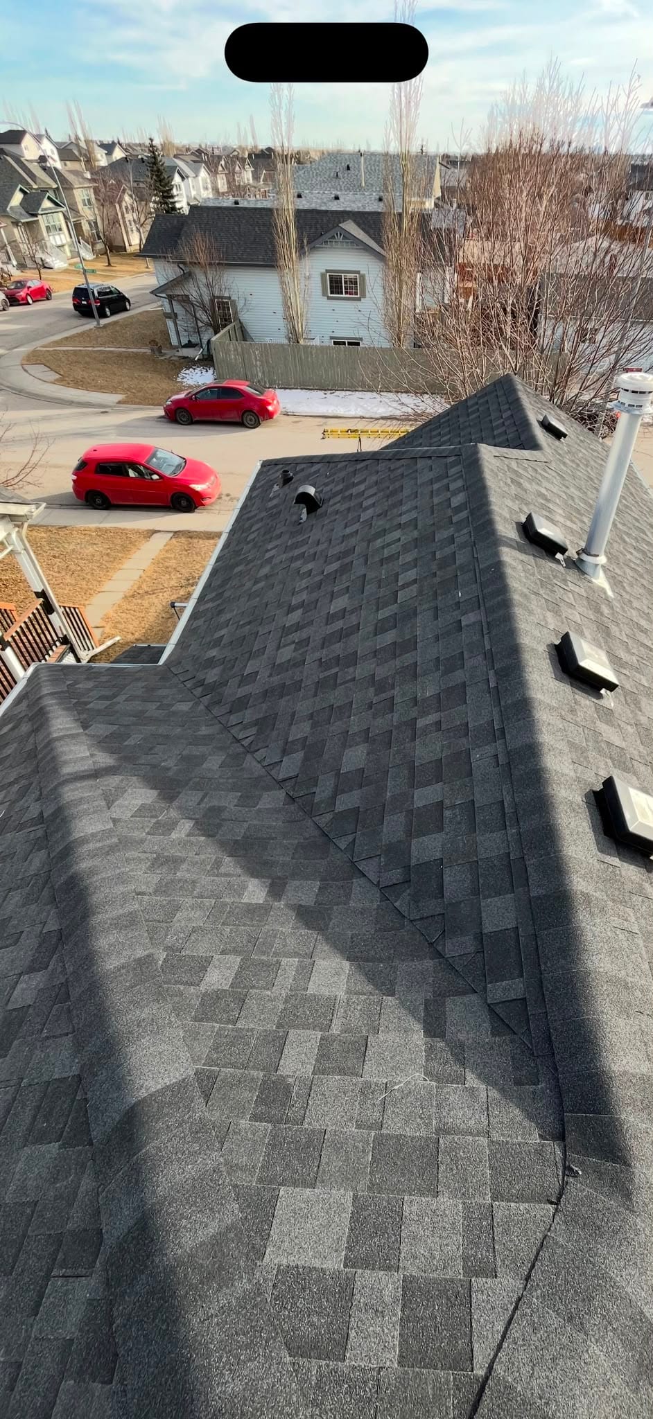 A finished shingle roof in a Calgary neighbourhood, box vents evenly spaced along the field
