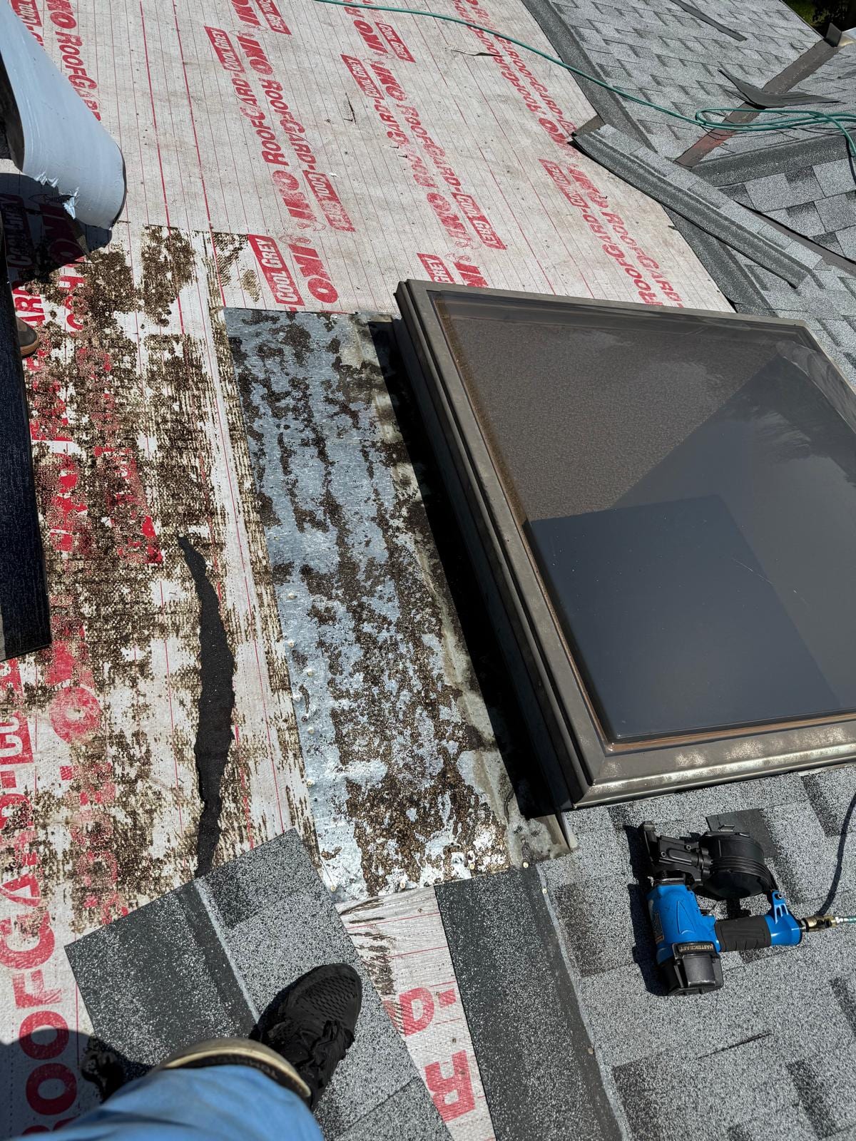 A Calgary shingle roof stripped to the underlayment during replacement, with the skylight flashing being redone