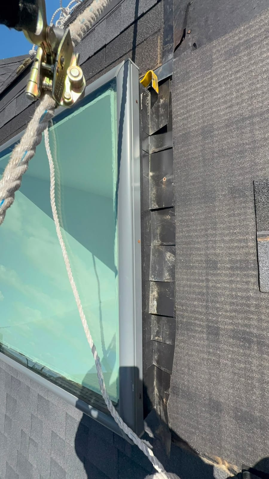 Step flashing woven into the shingle courses beside a skylight